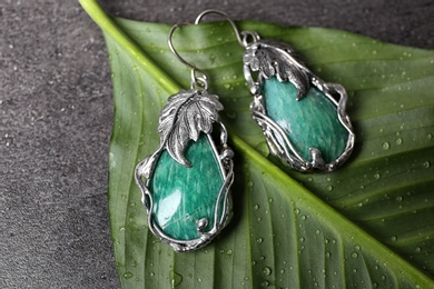 Photo of Beautiful pair of silver earrings with amazonite gemstones on green leaf, above view