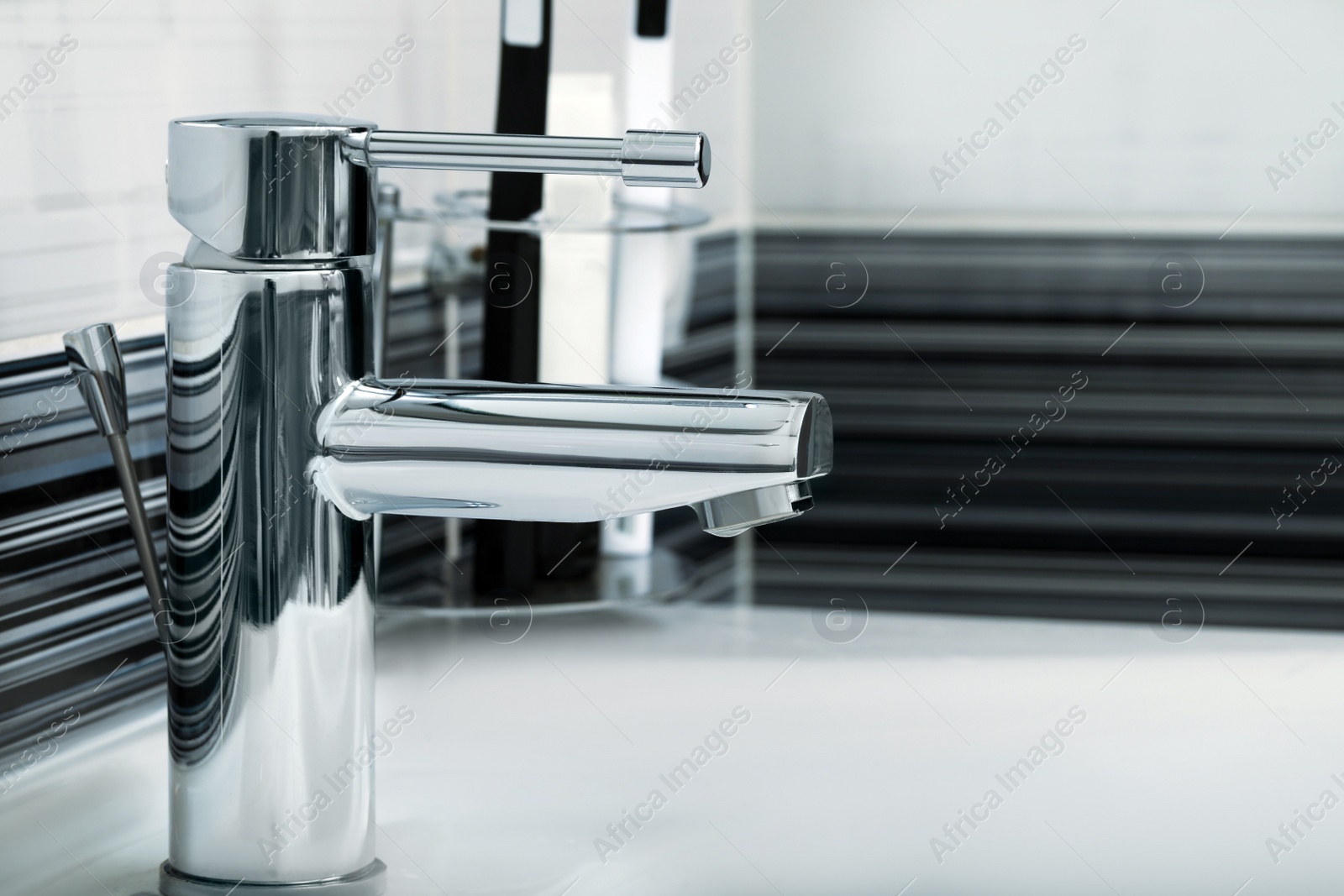 Photo of Clean white sink with shiny water tap in bathroom