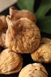 Tasty dried figs and green leaf on wooden board, closeup