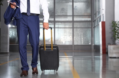 Businessman with black travel suitcase in airport. Space for text