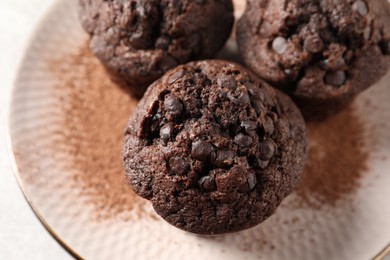 Photo of Delicious chocolate muffins and cacao powder on light table, above view