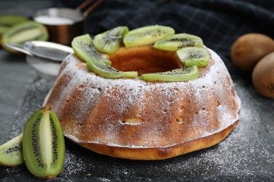 Homemade yogurt cake with kiwi and powdered sugar on black table