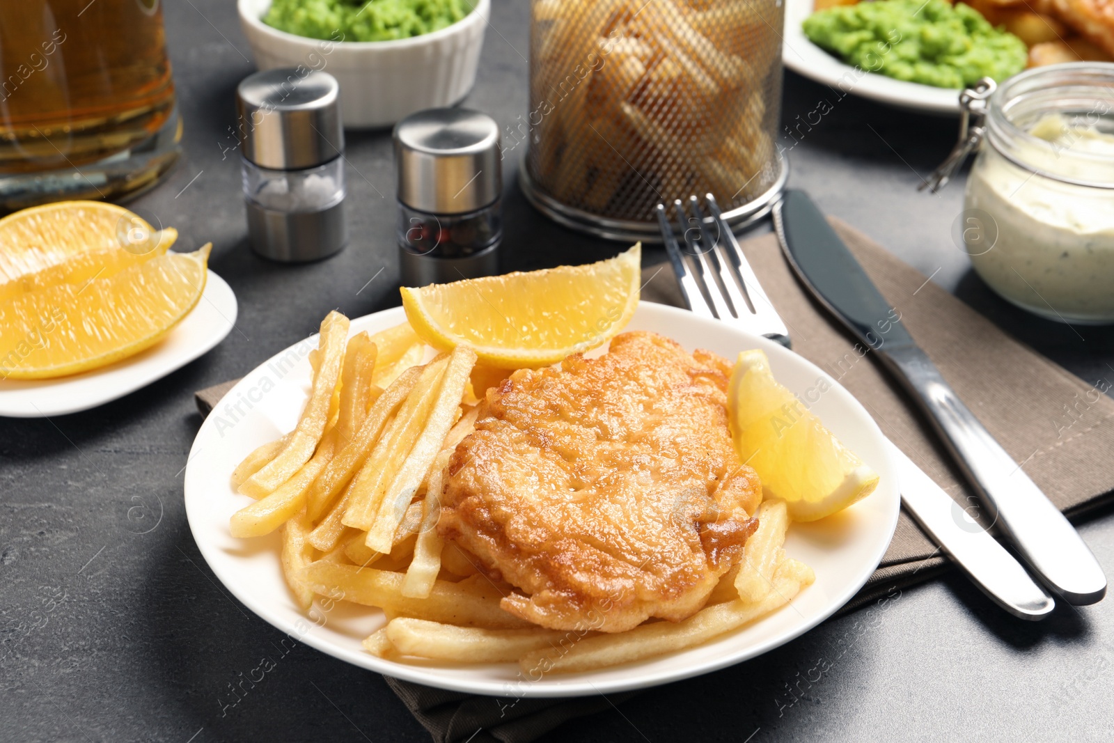 Photo of Plate with British traditional fish and potato chips on grey table