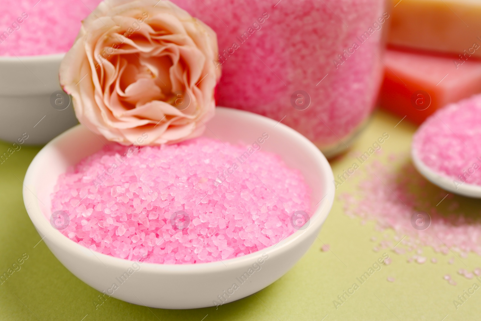 Photo of Aromatic sea salt and beautiful flower on pale green background, closeup