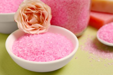 Photo of Aromatic sea salt and beautiful flower on pale green background, closeup