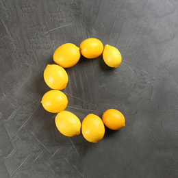 Photo of Letter C made with lemons on grey table as vitamin representation, flat lay