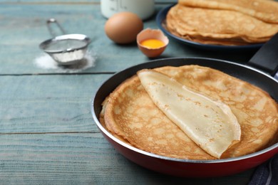 Delicious thin pancakes on blue wooden table, closeup