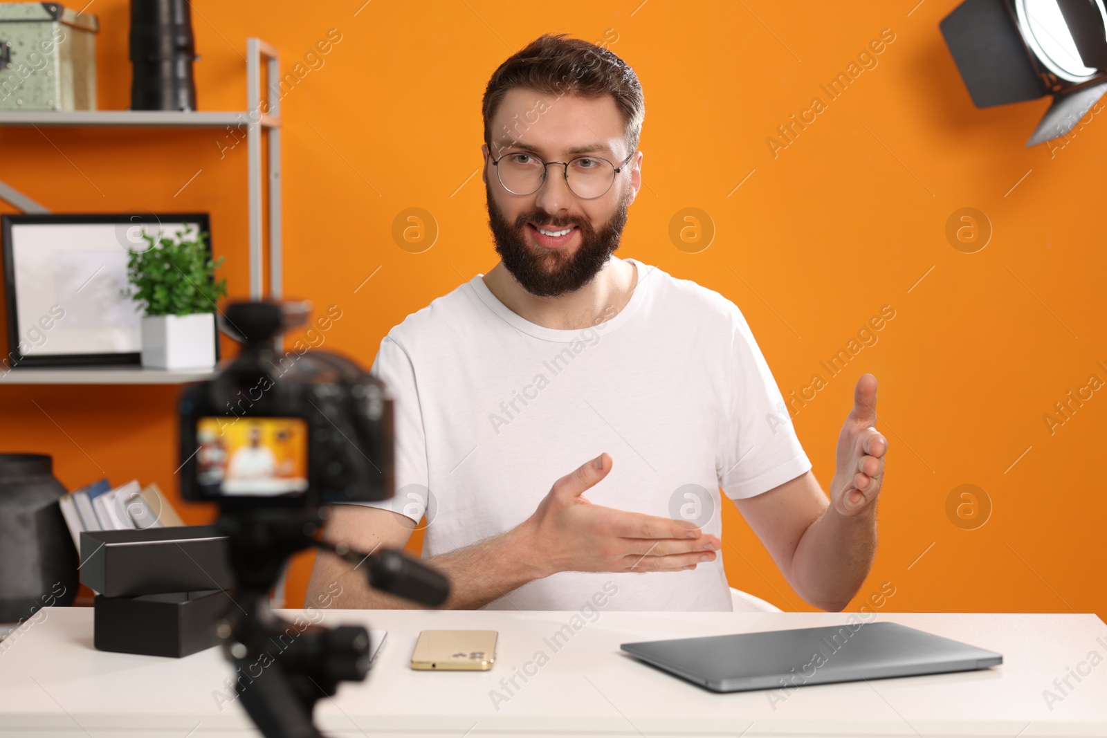 Photo of Smiling technology blogger explaining something while recording video at home