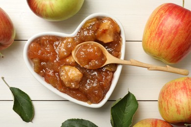Photo of Tasty apple jam in bowl and fresh fruits on white wooden table, flat lay