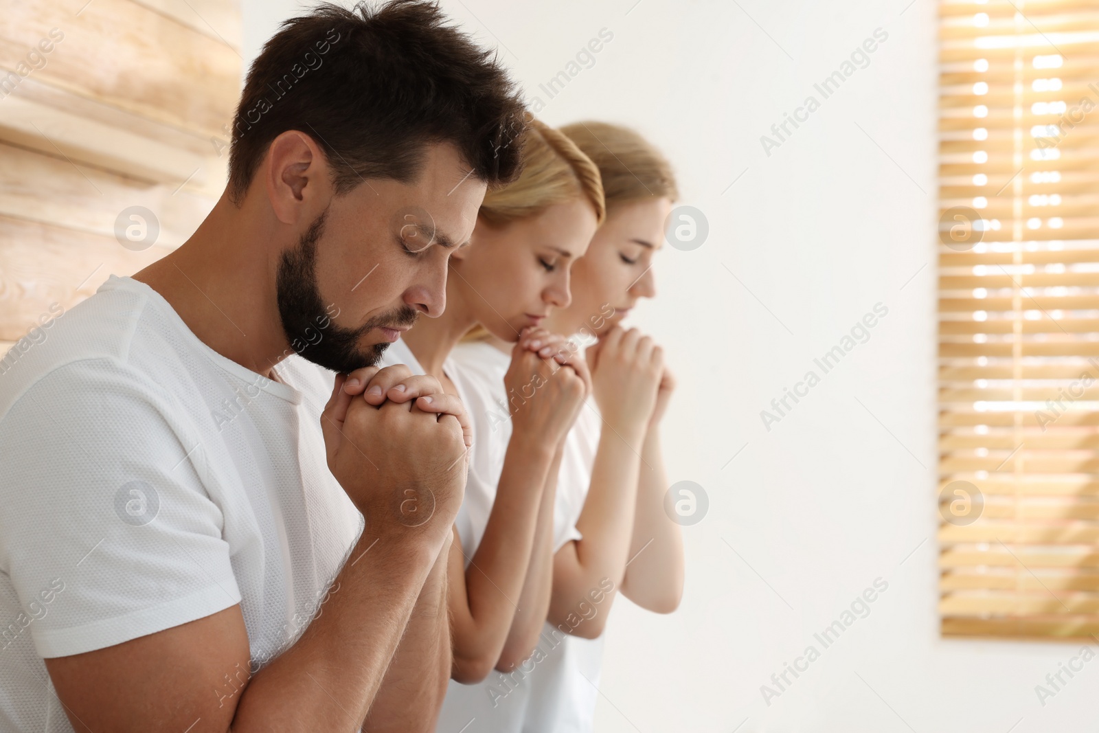 Photo of Group of religious people praying together indoors. Space for text