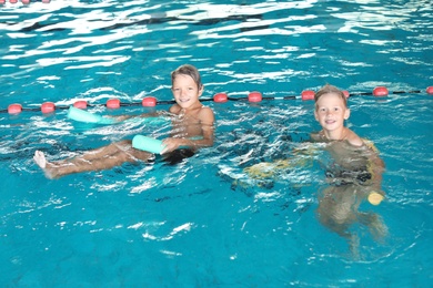 Photo of Little boys with swimming noodles in indoor pool