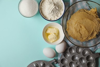 Photo of Ingredients for homemade walnut shaped cookies, dough and baking mold on turquoise table, flat lay. Space for text