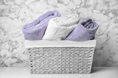 Basket with soft bath towels on table