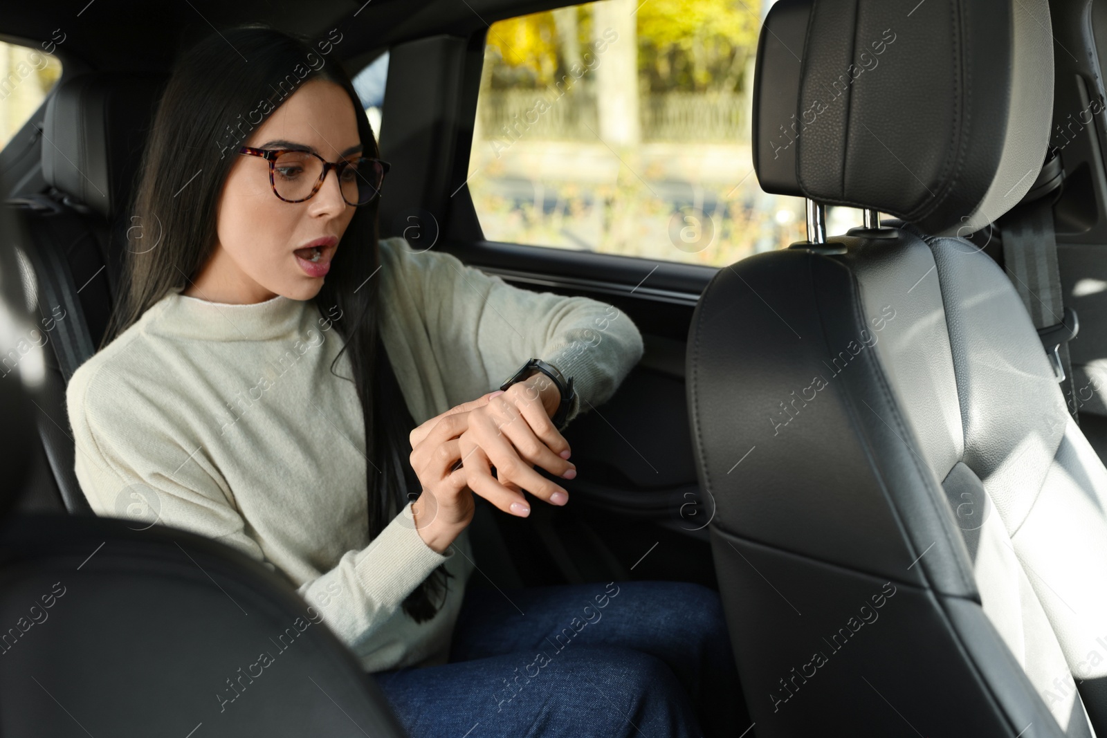 Photo of Emotional woman checking time on watch in car. Being late concept