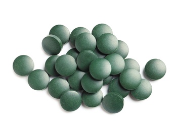 Photo of Heap of spirulina tablets on white background, top view