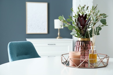 Photo of Beautiful bouquet with eucalyptus branches, candle and aromatic reed air freshener on white table indoors, space for text. Interior elements