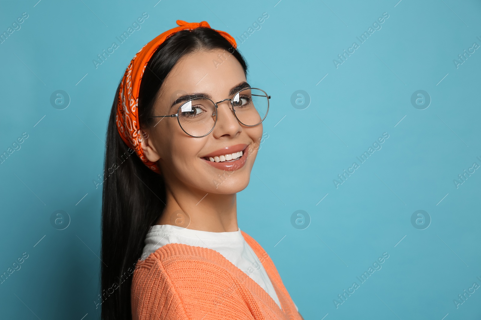 Photo of Young woman wearing stylish bandana on light blue background, space for text