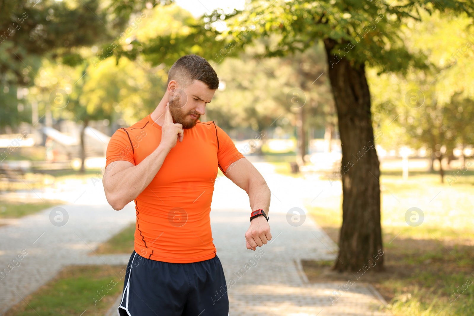 Photo of Young man checking pulse after workout in park