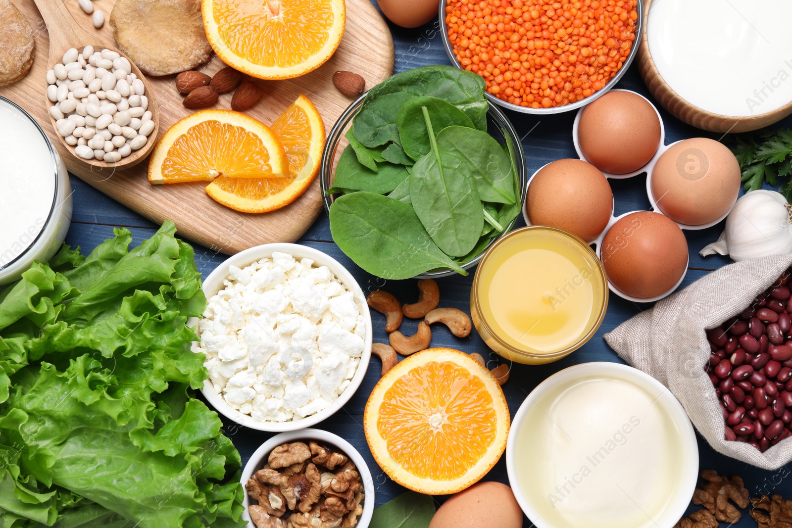 Photo of Set of natural food high in calcium on blue wooden table, flat lay