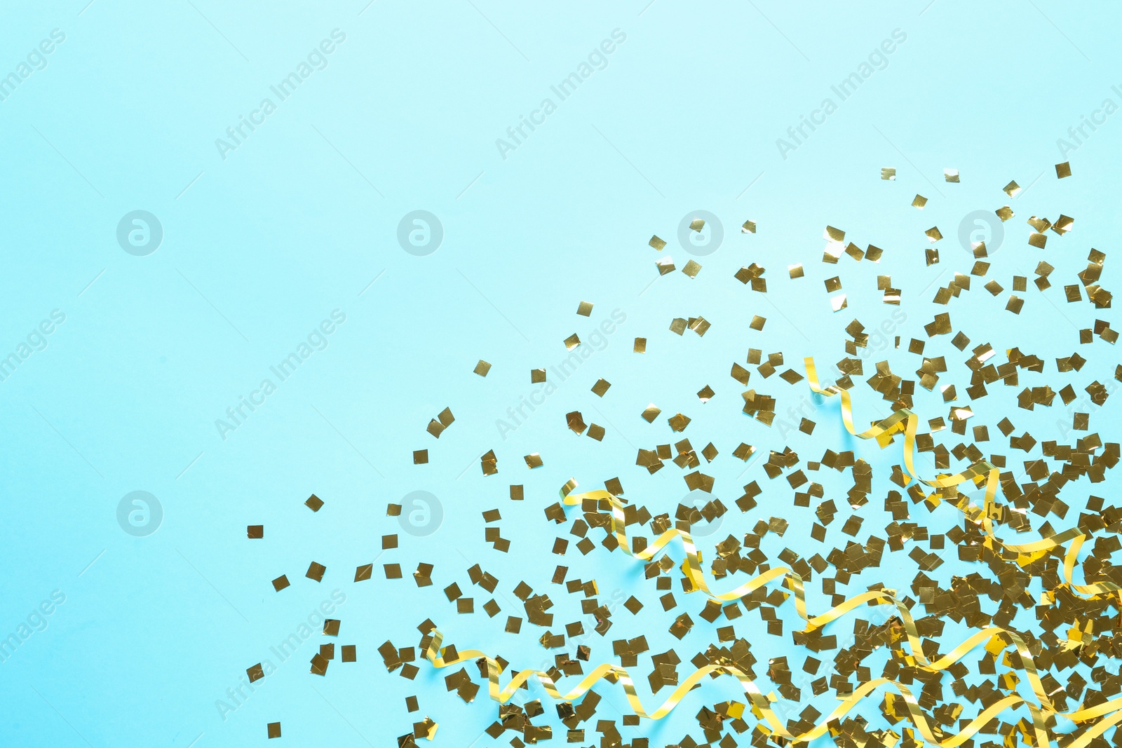Photo of Shiny golden confetti and streamers on light blue background, flat lay