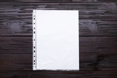 Photo of Punched pocket with paper sheet on brown wooden table, top view. Space for text