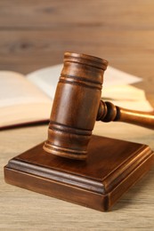 Photo of Wooden gavel and sound block on table, closeup