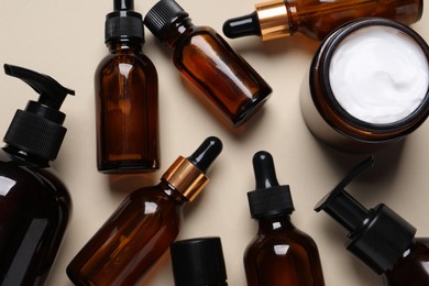 Photo of Face serums and other skin care products on beige background, flat lay