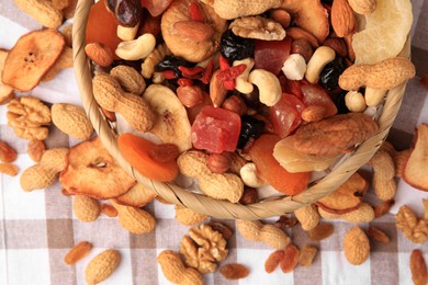 Photo of Mixed dried fruits and nuts on checkered tablecloth, flat lay