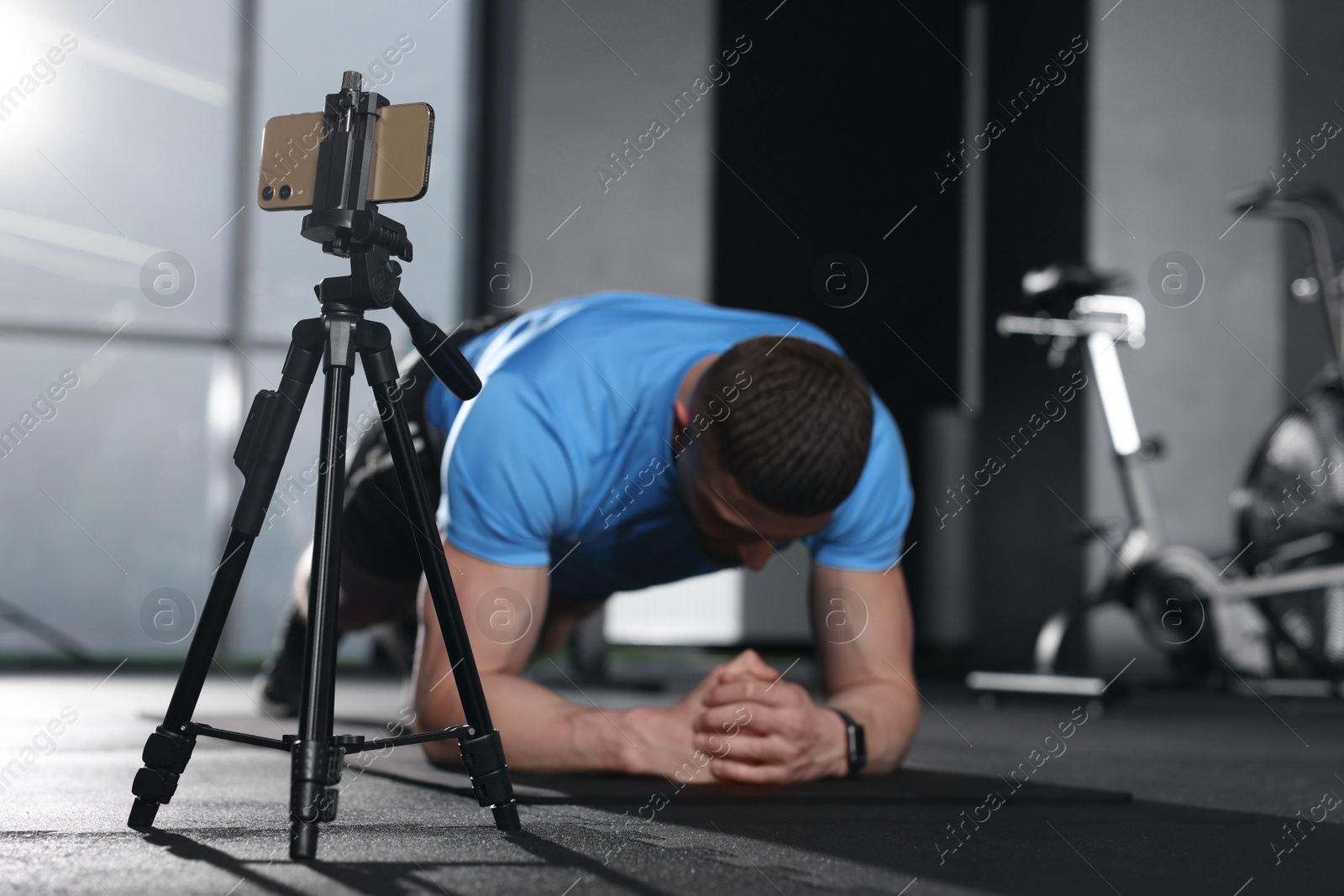 Photo of Trainer streaming online workout with phone at gym