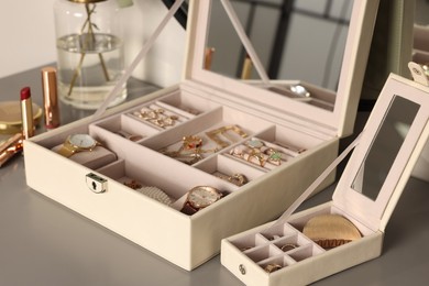 Elegant jewelry boxes with expensive wristwatches and beautiful bijouterie on grey table