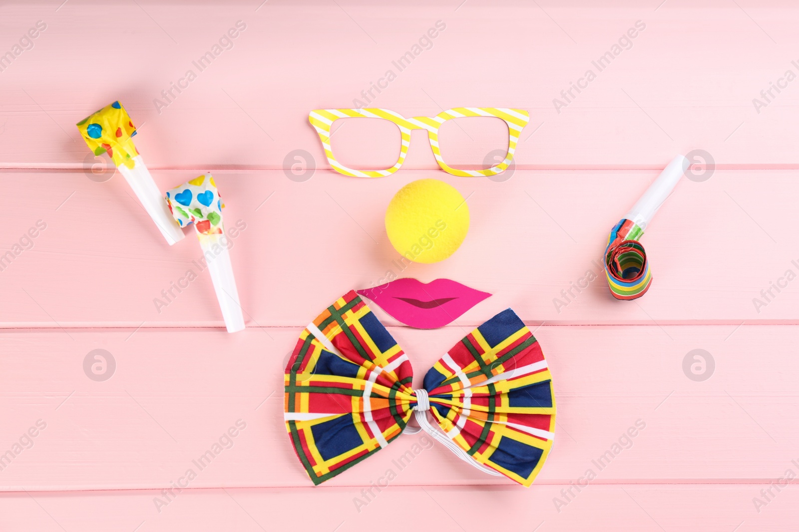 Photo of Flat lay composition with clown's items on pink wooden table