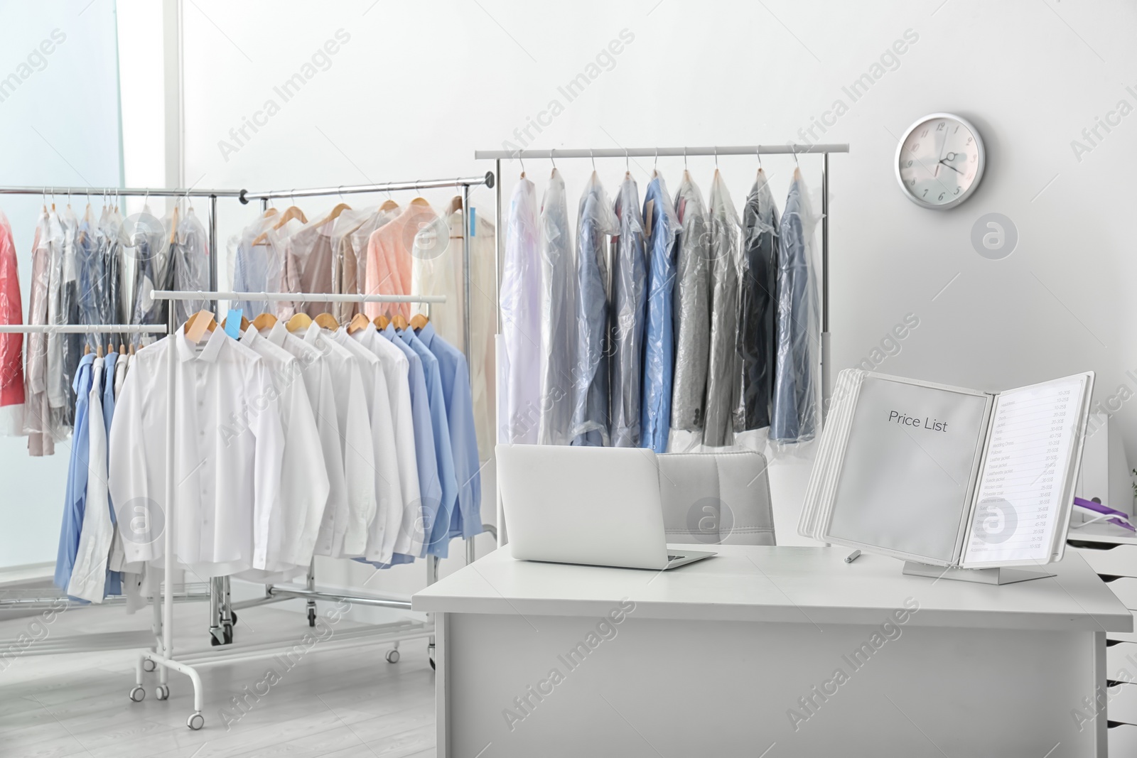 Photo of Workplace of receptionist with laptop and price list at dry-cleaner's