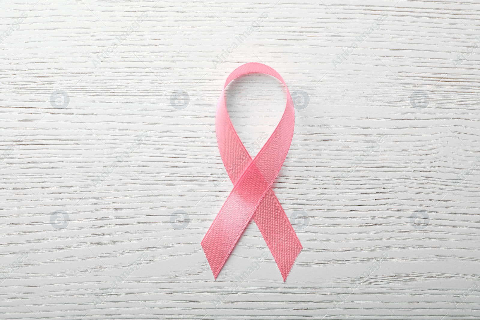 Photo of Pink ribbon on wooden background, top view. Breast cancer awareness concept