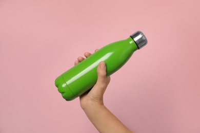 Photo of Woman holding modern green thermos on pink background, closeup