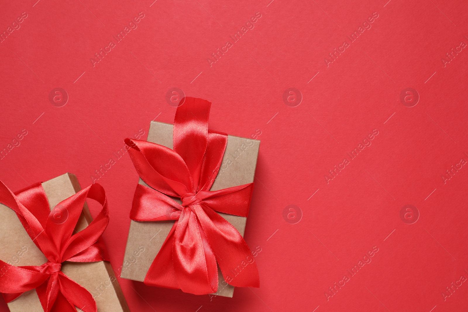 Photo of Beautiful gift boxes on red background, flat lay. Space for text