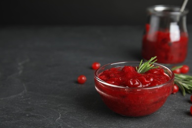 Photo of Bowl of cranberry sauce with rosemary on grey table, closeup. Space for text