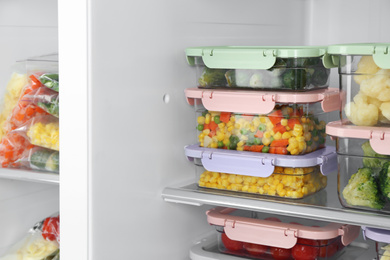 Containers with different frozen vegetables in refrigerator