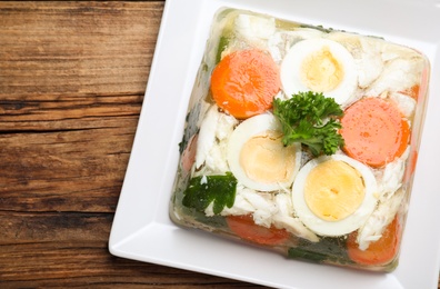 Photo of Delicious fish aspic served on wooden table, top view