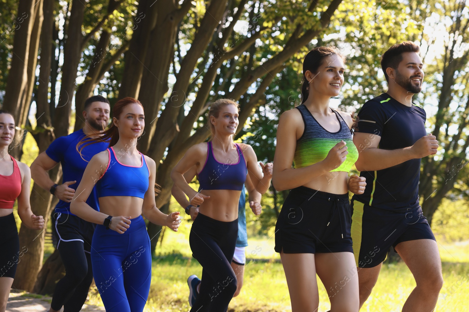 Photo of Group of people running in park on sunny day