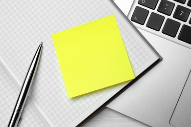 Notebook with blank sticky note, laptop and pen on white wooden table. Space for text