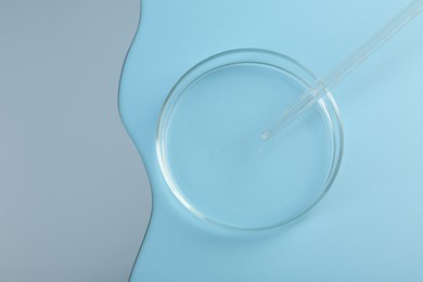 Empty petri dish, pipette and mirror on light blue background, flat lay