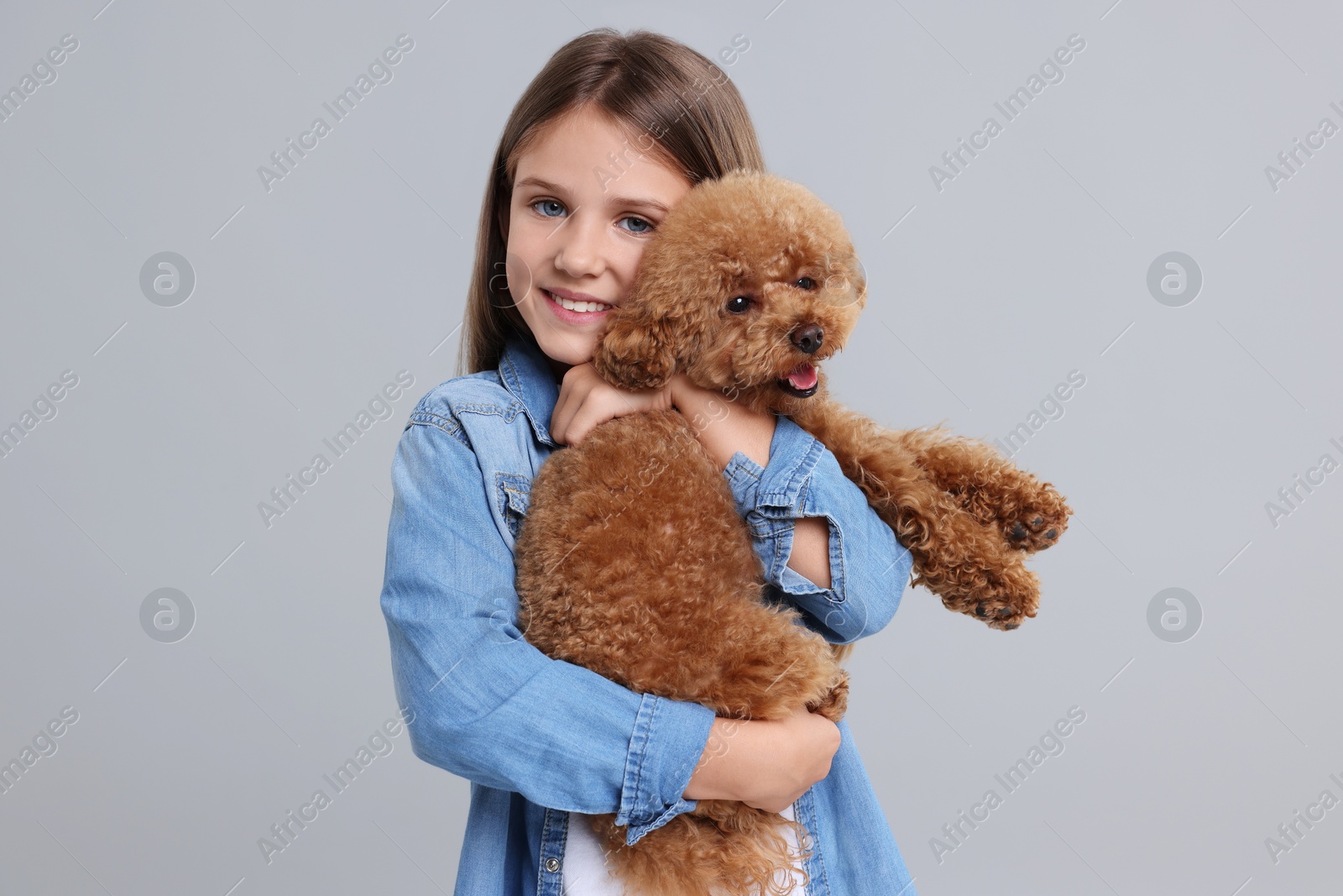 Photo of Little child with cute puppy on light grey background. Lovely pet