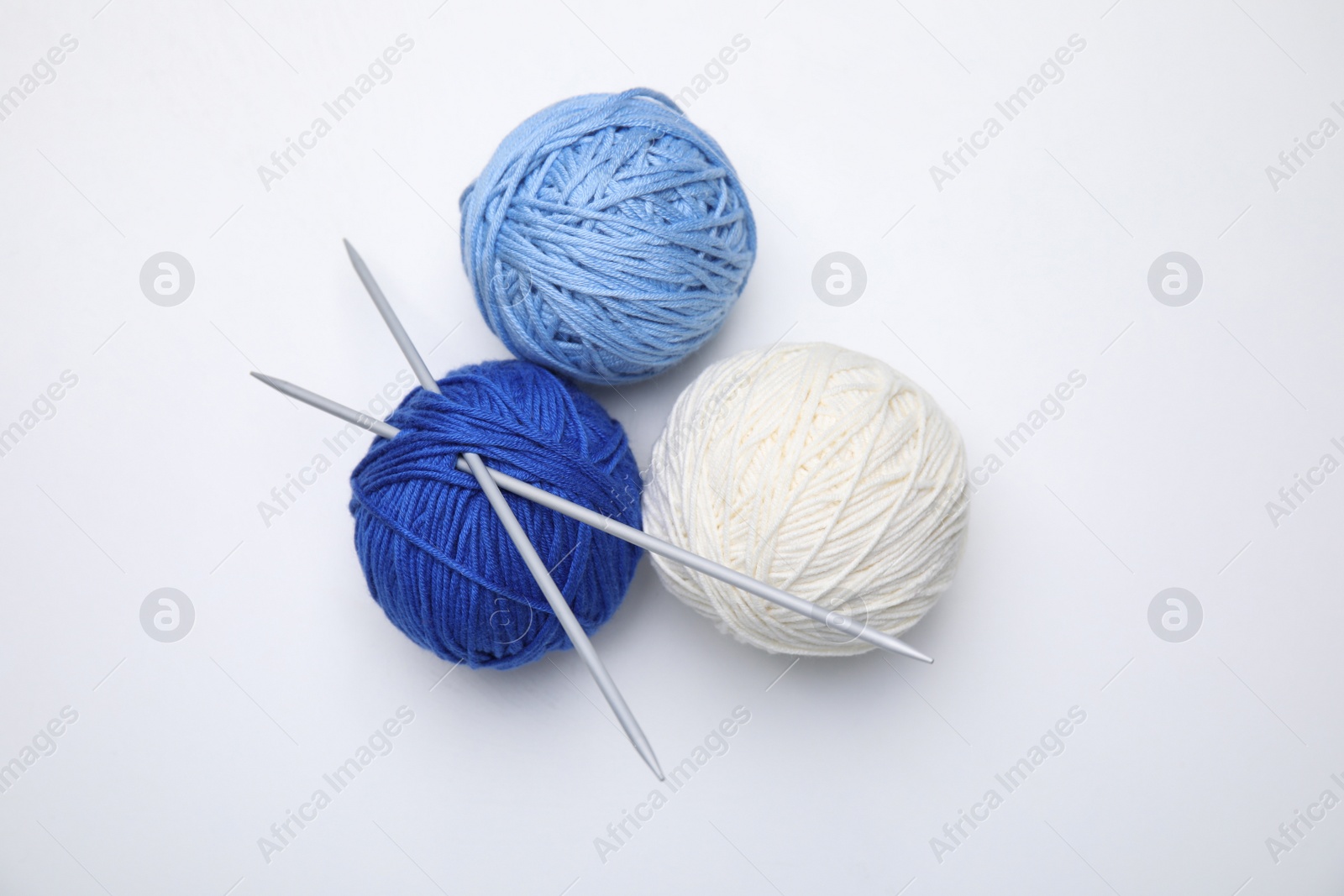 Photo of Soft woolen yarns with knitting needles on white background, top view