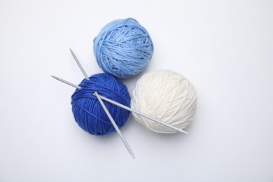 Photo of Soft woolen yarns with knitting needles on white background, top view