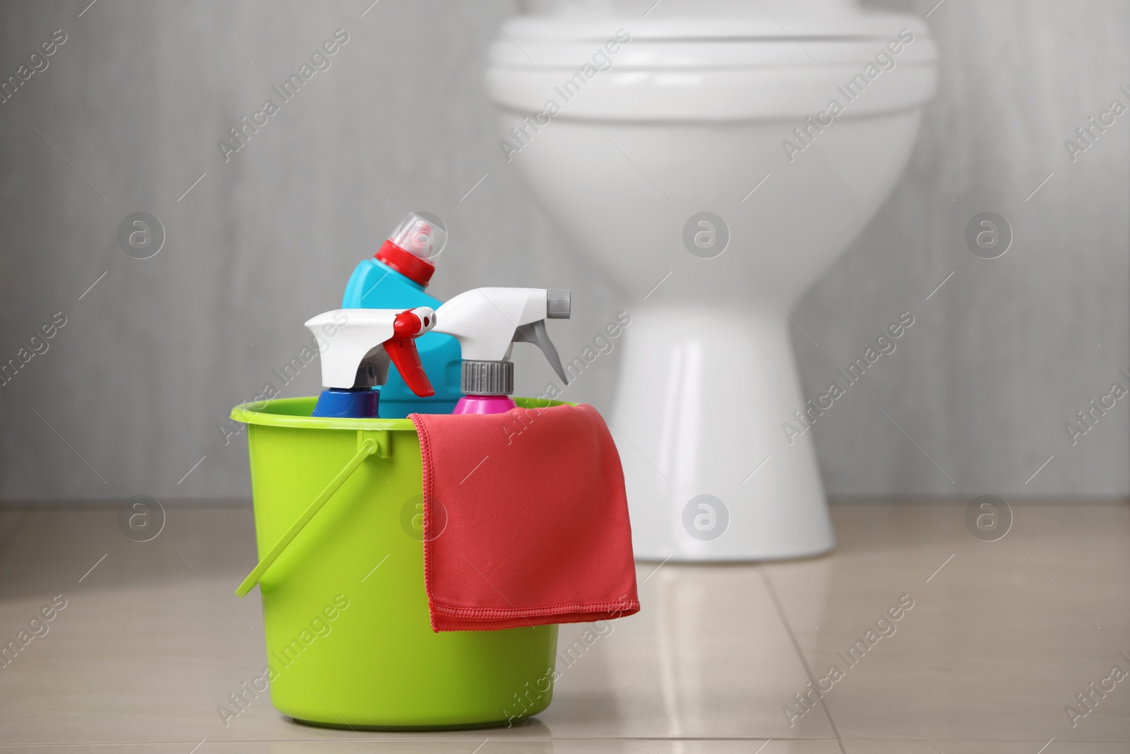 Photo of Bucket with toilet cleaning supplies on floor indoors, space for text