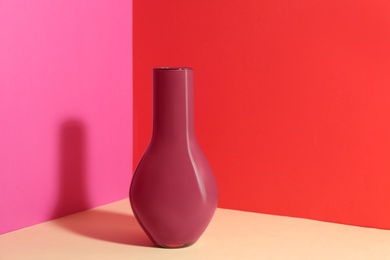 Stylish empty ceramic vase on color background, space for text