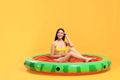 Photo of Happy young woman with beautiful suntan on inflatable mattress against orange background