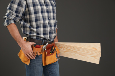 Photo of Carpenter with wooden planks on dark background, closeup