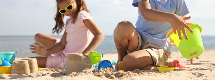 Image of Cute little children playing with plastic toys on sandy beach. Banner design