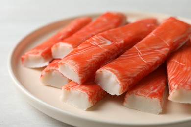Photo of Plate of fresh crab sticks on white table, closeup